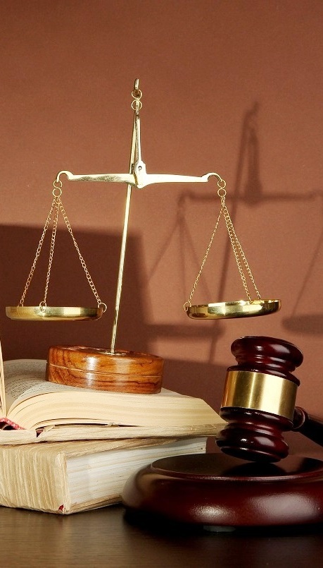 Golden scales of justice, gavel and books on brown background